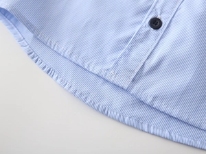 Detail of blue striped cotton shirt with curved hem, neat stitching, and resin button