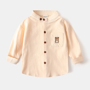 Détail de chemise en coton jaune clair avec col en V et broderie d'ours sur la poche