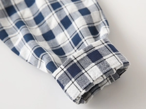 Gros plan du poignet d'une chemise à carreaux bleu et blanc montrant la texture