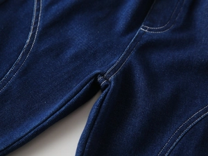 Detail view of indigo blue denim fabric with white contrast stitching on boy's jeans