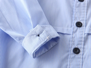 Detailed macro view of blue vertical stripes and dark buttons on boy's cotton shirt sleeve