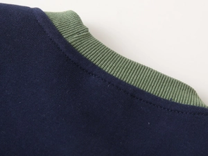 Detail of navy cotton sweatshirt featuring a contrast green ribbed knit crew neckline