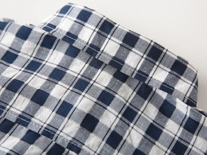 Gros plan détaillé du col et des coutures d'une chemise à carreaux bleus pour garçon