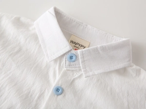 Detail shot of a boy's white cotton shirt collar with light blue buttons and texture