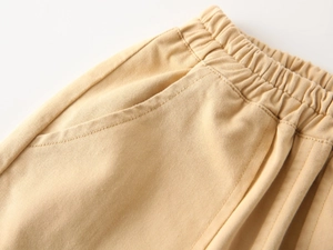 Detail of the elastic waistband and side pocket on boys' beige cotton chino trousers