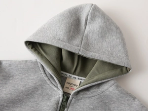 Détail d'un sweat à capuche enfant avec tissu gris chiné et doublure vert olive