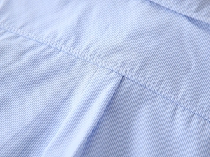 Macro shot of blue and white striped cotton shirt showing precise back pleat stitching