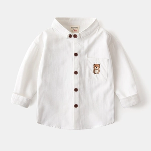 Détail d'une chemise en coton blanc avec broderie ours et boutons de couleur marron foncé