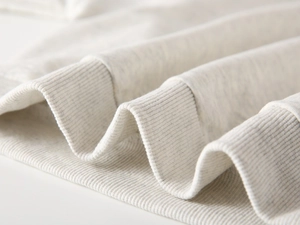 Close-up of the ribbed cuff and soft marl white cotton fabric texture on a child sweatshirt