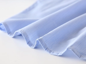 Close-up of light blue striped cotton fabric with smooth texture and soft pleats