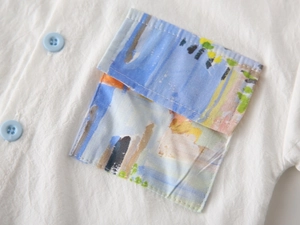 Close-up of boys white cotton shirt featuring a colorful abstract art chest pocket