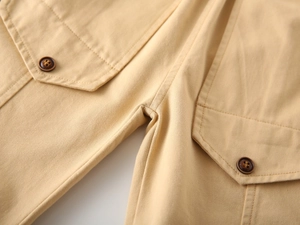 Close-up of boys khaki cargo trousers showing detailed stitching and button pockets