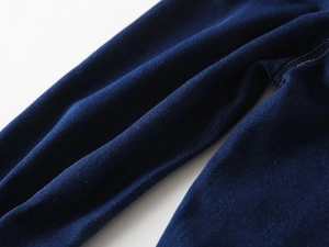 Detailed macro view of dark indigo denim fabric with contrasting cream stitching