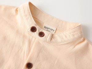 Détail rapproché du col mao et des boutons marron sur la chemise en coton pêche