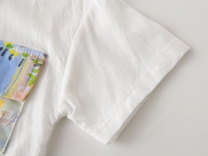 Detail view of cotton shirt sleeve and colorful artistic pocket on a white base