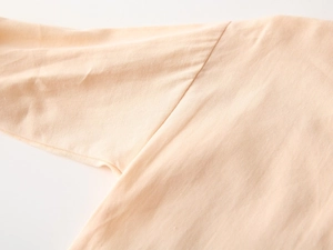 Détail de la couture d'épaule sur un haut en maille de coton crème pour garçons
