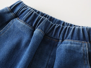 Close-up of elastic waistband on dark blue denim jeans with orange contrast stitching detail