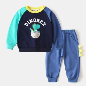 Détail de la broderie dinosaure et des bords dentelés sur le pantalon de jogging bleu