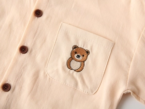 Détail d'une chemise pour enfant beige avec broderie ours sur la poche de devant