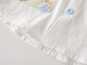 Detail view of cotton boy's shirt showing white fabric texture and a light blue button