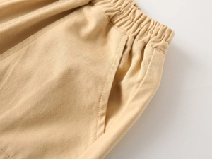 Detail of boys khaki trousers featuring elastic waistband and durable twill fabric