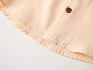 Vue macro du tissu en coton beige clair avec bouton marron et coutures détaillées