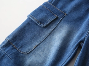 Macro view of blue wash denim cargo pocket with yellow contrast stitching on boys' jeans