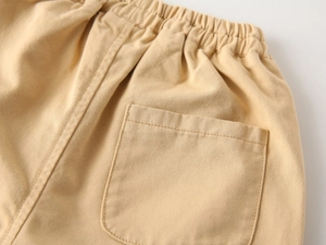 Detailed view of beige cotton twill pants with elastic waist and square back pocket