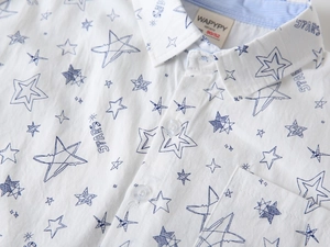 Detail of white cotton boy shirt showing star pattern, collar label, and button texture