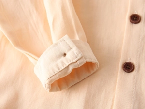 Vue macro des poignets et boutons bruns sur une chemise en sergé de coton beige