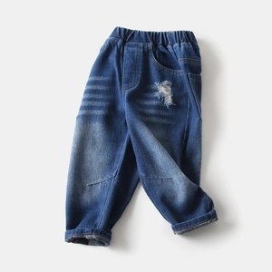 Detail of boys distressed denim jeans featuring elastic waistband and ripped knees design
