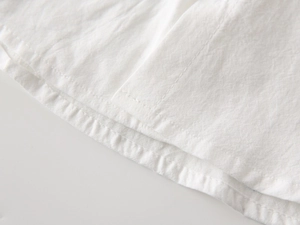 Close-up of white cotton shirt hem with double stitching and textured fabric detail
