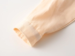 Gros plan du poignet d'une chemise à manches longues abricot clair au tissu sergé