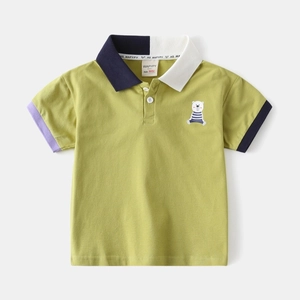 Détail macro du polo enfant avec broderie ours et col contrasté en maille de coton
