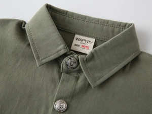 Détails des boutons étoilés argentés et étiquette de marque sur chemise garçon olive