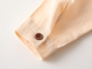 Gros plan d'un poignet en sergé de coton avec bouton décoratif marron et coutures fines