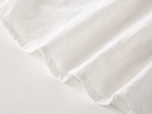 Macro view of white cotton fabric detail showing smooth texture and soft folds