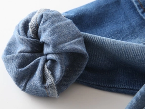 Macro detail of boys denim jeans showing orange stitching and inner overlock seam finish