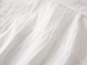 Close-up of white cotton fabric texture and precise stitching on the child shirt