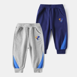 Détail de la broderie dinosaure et du design color-block sur le pantalon de jogging