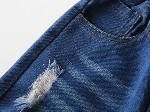 Detailed close-up of dark blue denim jeans featuring distressed ripped texture and stitching