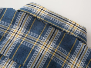 Gros plan du col d'une chemise à carreaux pour garçon montrant les coutures et le motif bleu et jaune