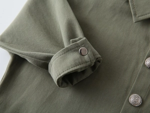 Gros plan sur le tissu sergé vert armée et les boutons en métal gravés de la chemise