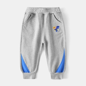 Détail du jogging gris pour enfant avec broderie dinosaure et empiècements bleus