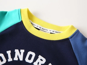 Détail du sweat enfant avec manches raglan contrastées et col côtelé jaune vif