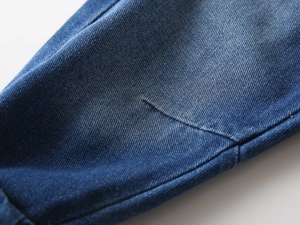 Detailed close-up of dark blue denim fabric texture and quality stitching for boys' jeans