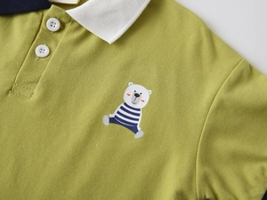 Détail du polo pour garçon en coton vert avec col blanc et broderie d'ours polaire