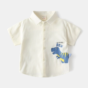 Détail d'une chemise bébé crème à manches courtes avec imprimé dinosaure bleu