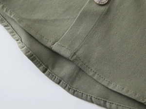 Détail de chemise pour garçon en sergé de coton vert armée avec bouton en métal et couture
