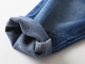 Detailed close-up of denim jeans hem with neat stitching and natural rolled cuff texture